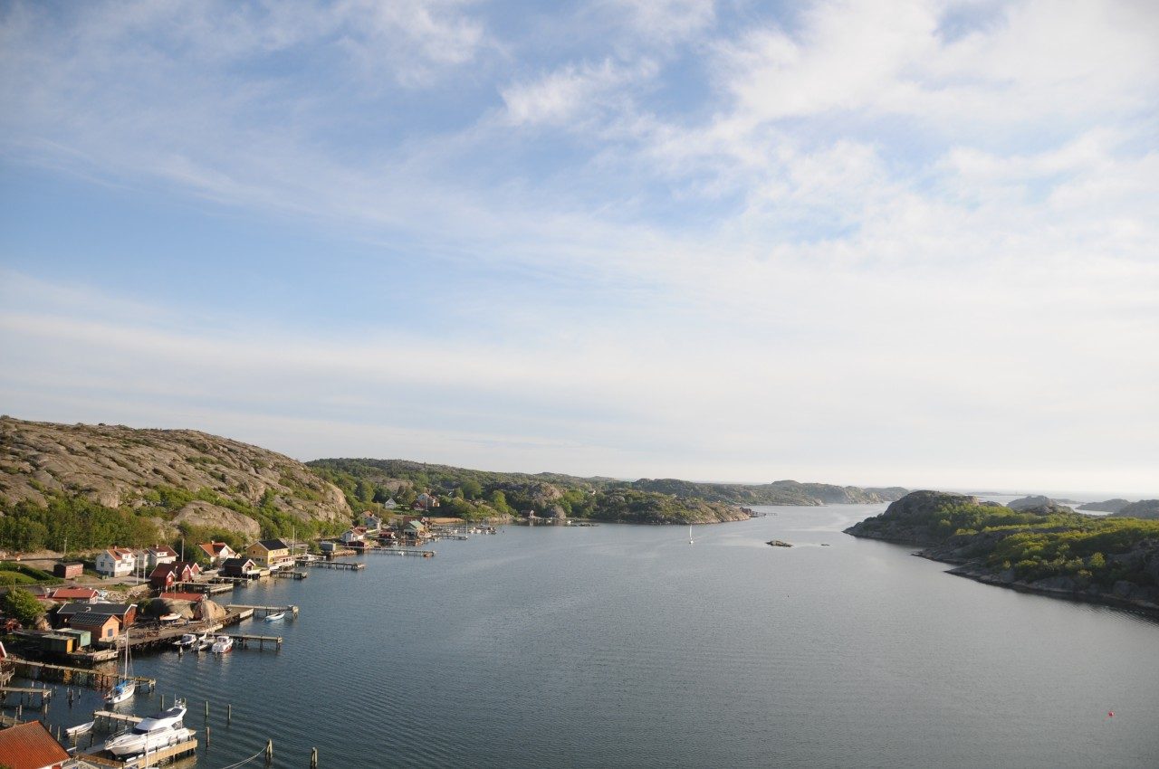 Utsikt över sundet med bebyggelse längs stranden och kala klippor