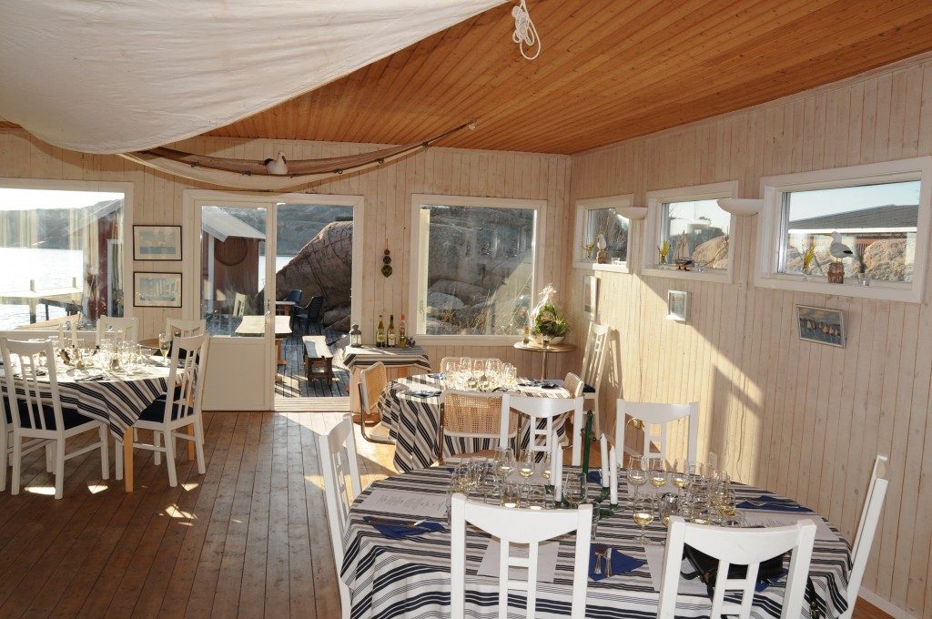 Matsalen med dukade bord, randiga dukar och fönster mot vattnet